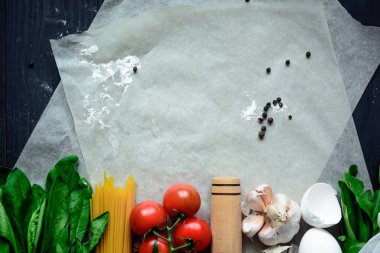 Gıda arka plan. Düz taze domates, yumurta, un, fesleğen, makarna ve sarımsak koyu siyah ahşap arka plan üzerinde yatıyordu. Soldaki kopya alanı ile üstten görünüm