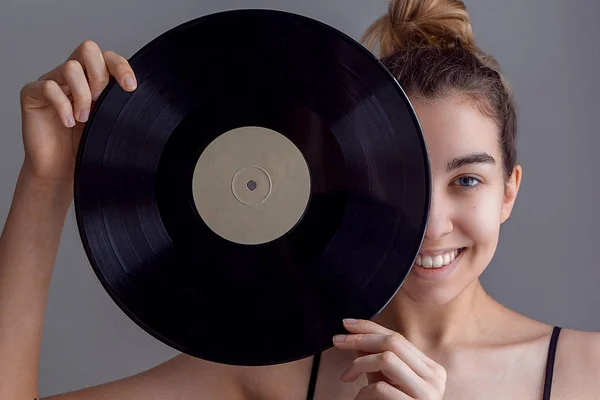 Güzel kız portre bir Lp microgroove vinil kaydı parlak arka planda tutan,