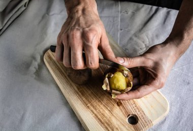 Soyulmuş derileri ile taze sıcak haşlanmış patates. Yemek veya yemek, masada hazır tutan el. Kavram ve fikir gıda rustik hala yaşam tarzı