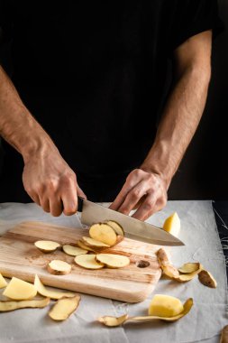 Şefin eli, masada yemek pişirmek için taze ve lezzetli patatesleri kesiyor. Sağlıklı gıda.