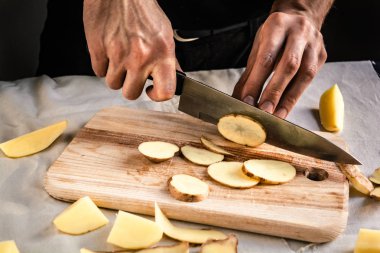 Şefin eli, masada yemek pişirmek için taze ve lezzetli patatesleri kesiyor. Sağlıklı gıda.