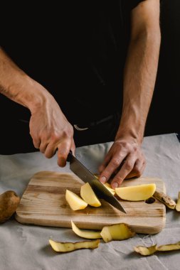 Şefin eli, masada yemek pişirmek için taze ve lezzetli patatesleri kesiyor. Sağlıklı gıda.