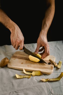 Şefin eli, masada yemek pişirmek için taze ve lezzetli patatesleri kesiyor. Sağlıklı gıda.