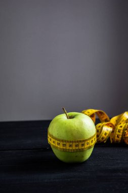 Teyp ölçme yeşil elma diyeti sembolü olarak sarılmış.