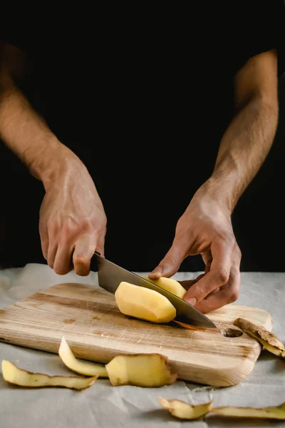 Şefin eli, masada yemek pişirmek için taze ve lezzetli patatesleri kesiyor. Sağlıklı gıda.