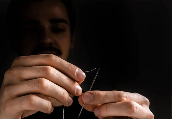 Man tailor threading a needle