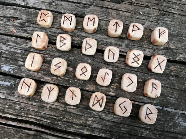 A stack of wooden runes at forest. Wooden runes lie on a old wood background. Runes are cut from wooden blocks. On each rune symbol for fortune telling is designated. — Stock Photo, Image