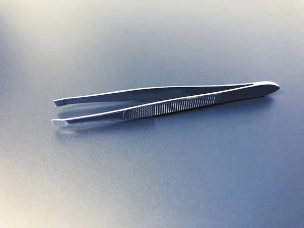 Metal Steel tweezers on gray and blue background. — Stock Photo, Image