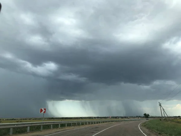 La pluie tombe d'un nuage sur fond de route et de ciel ensoleillé — Photo