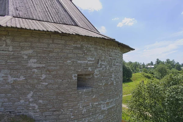 Round tower of a medieval stone fortress with a wooden roof on a natural background close up