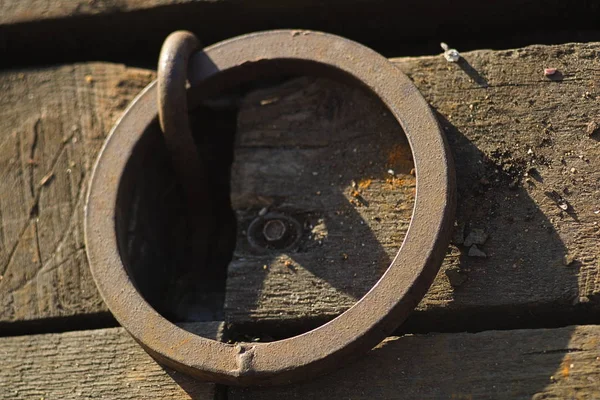 Παλιό σκουριασμένο μεταλλικό δαχτυλίδι για αγκυροβόλια πλοίων σε ξύλινο δάπεδο προβλήτα. Κοντινό. — Φωτογραφία Αρχείου