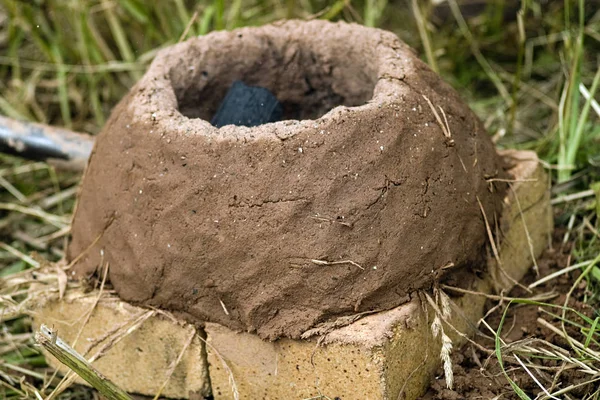 Eine Feuerstelle aus Ton und Stroh ist eine Rekonstruktion historischer Handwerkskunst. Mittelalterfest unter freiem Himmel. ein laufender Ofen zur Reparatur von Metallprodukten, zur Markierung von Haut und Tieren. — Stockfoto