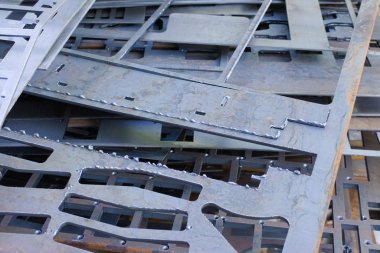 Lazer kesimden sonra delikli metal levhalar birbirinin üzerine uzanır. Geri dönüşüm için hazırlanan metal işleme atıkları.