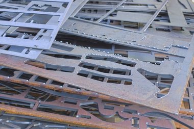 Lazer kesimden sonra delikli metal levhalar birbirinin üzerine uzanır. Geri dönüşüm için hazırlanan metal işleme atıkları.