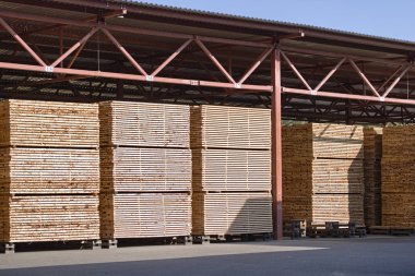 Testere panoları yaz açık havada bir metal gölgelik altında bir depoda yığılmış. Doğal ahşap kurutma. Ahşap endüstrisi.