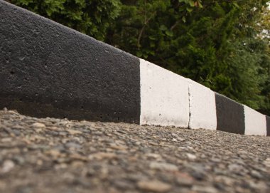 Bir sokak sınırı beyaz ve siyah yolun arka planda boyalı ve yaz closeup yeşil yeşillik. Yol güvenliği