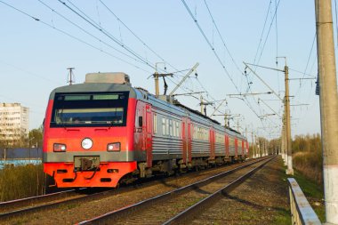 Kırmızı elektrikli tren yaza doğru demiryolu hatları boyunca seyahat ediyor. Banliyö yolcu demiryolu hizmeti.