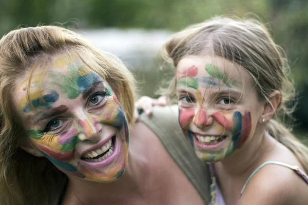 Mother and daughter with painted faces having fun in the garden