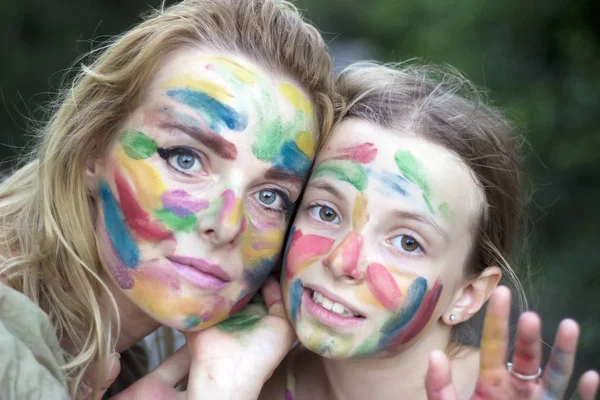 Mother and daughter with painted faces having fun in the garden