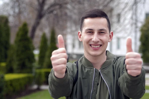 Portrait of young man with thumbs up in the public park