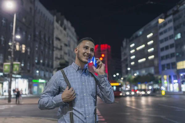 Handsome Young Adult in Illuminated City Street Talking over his Smart Phone
