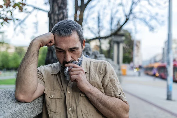 Portrait of a Mid Adult Depressed  Man with Beard Smoking a Cigarette in the City Streets