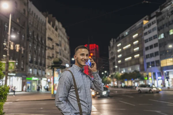 Handsome Young Adult in Illuminated City Street Talking over his Smart Phone