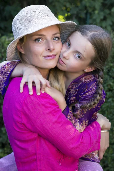 Portrait of woman in pink and white hat and her beautiful daughter in love
