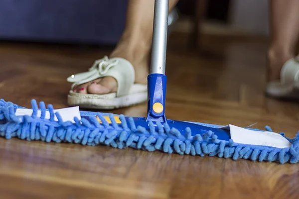 Low Angle View of Young Woman Mopping Kitchen Floor with Focus on Shiny Clean Floor and Mop