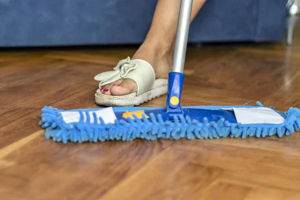 Low Angle View of Young Woman Mopping Kitchen Floor with Focus on Shiny Clean Floor and Mop