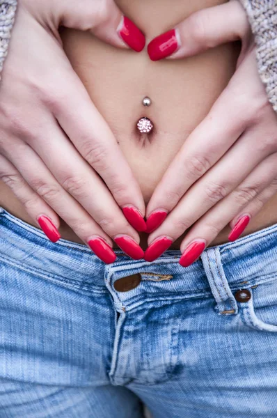 Woman with piercing making heart shape on her belly