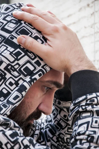 Young depressed man suffering from anxiety and feeling miserable cover his face with his hands and cry leaning on the wall