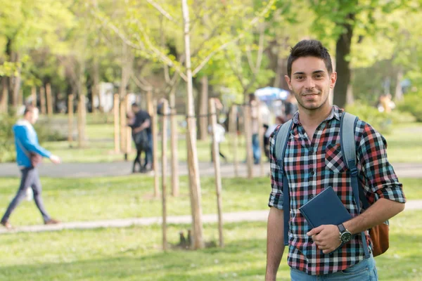 College student with book.Student guy doing homework in the park.