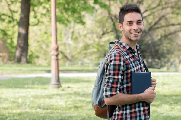 College student with book.Student guy doing homework in the park.