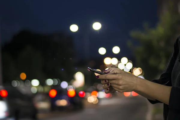Woman Using Cell Phone in the City Street with Illuminated Night Lights View