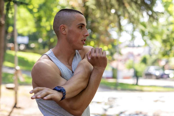 Handsome Muscular Man in Sportswear Stretching in Public Park, Ready for Workout