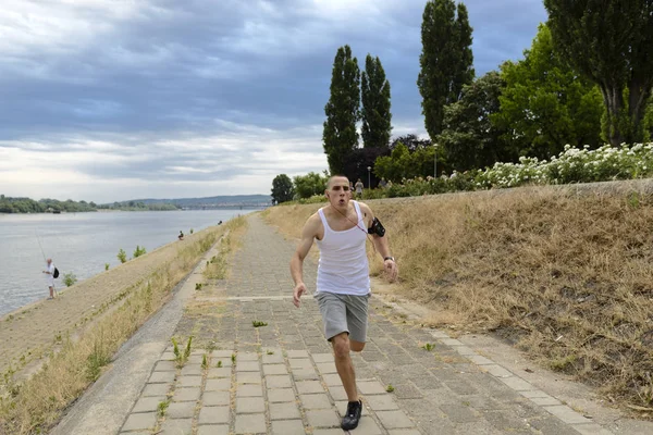 young man runs by the river
