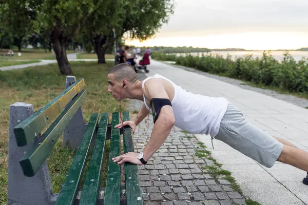 Determined young athlete doing pushups on park bench, Outdoor excercise