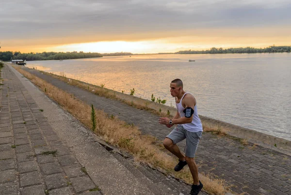 Young man jogging or running along the river Danube at sunset. Unusual point of view. Sport, lifestyle concept, copy space.