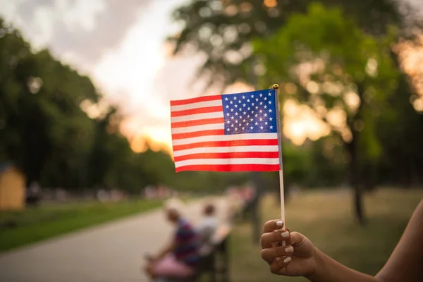 Woman hand is waving US flag outdoors on the Independance day.