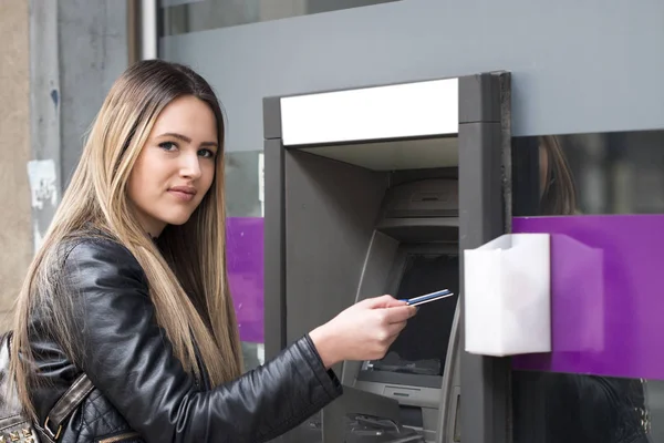 woman hand inserting credit card to ATM. Hand inserting ATM card into bank machine to withdraw money. Young Woman using Bank ATM cash machine on the street
