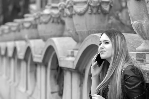 Gorgeous pensive woman looking away while contacting on mobile phone via application and strolling at street.Dreamy hipster girl enjoying leisure time while walking at spring urban setting with gadget