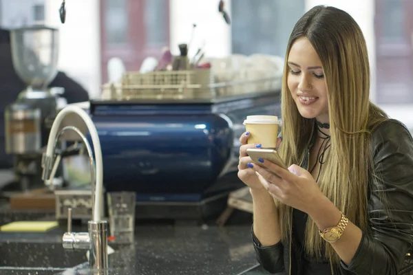 Image of woman talking on phone in cafe. Young beautiful girl sitting in a coffee shop and using her mobile phone