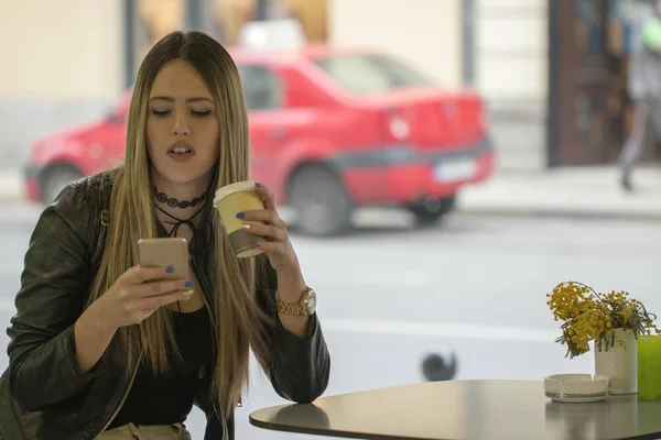 Image of woman talking on phone in cafe. Young beautiful girl sitting in a coffee shop and using her mobile phone