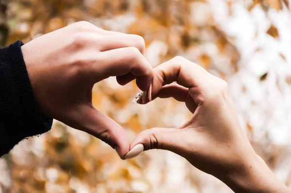 Close up view of couple in love making heart shape with fingers