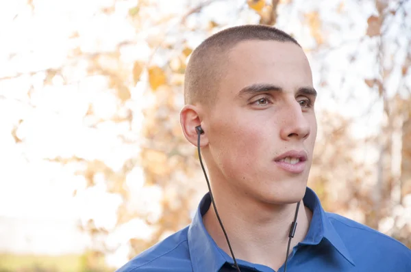 Portrait of handsome young man with earphones in the park listening to music