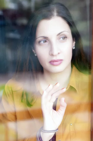 Portrait of sad woman looking through the window