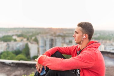 Eğitim sonrası bir şehir çatı üzerinde bir akıllı telefon veya cep telefonu fotoğraf veya gün batımı resmi alarak Manly ama romantik spor adam