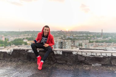 Arka planda gün batımında kulaklıklar tarafından müzik dinleme Manly ama romantik spor adam