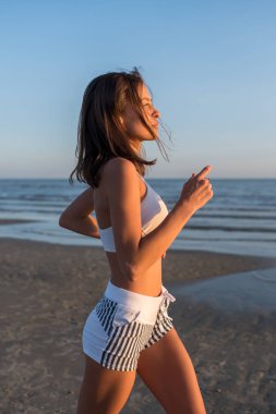 Genç ince güzel kadın olumlu ruh hali olan gün batımında çalıştırmak